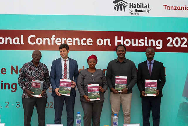 Attendees gather in front of a banner displaying "National Conference on Housing 2026.