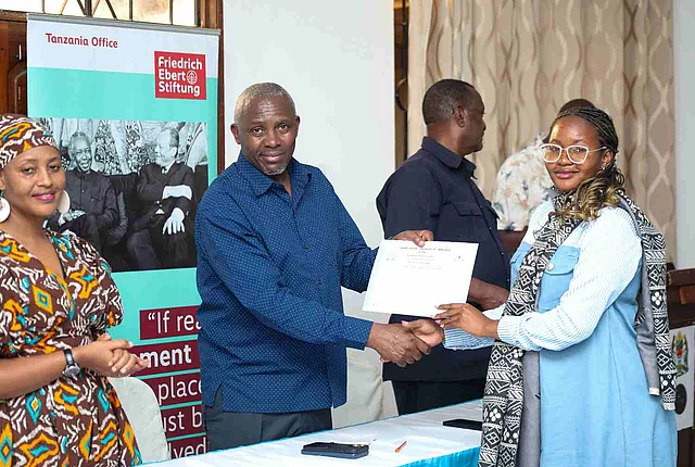 One of the workshop participants receiving a certificate from Mr. Pertenus Rwechungura, the General Secretary of TAMICO, with FES Project Officer, Anna Mbise on the left.